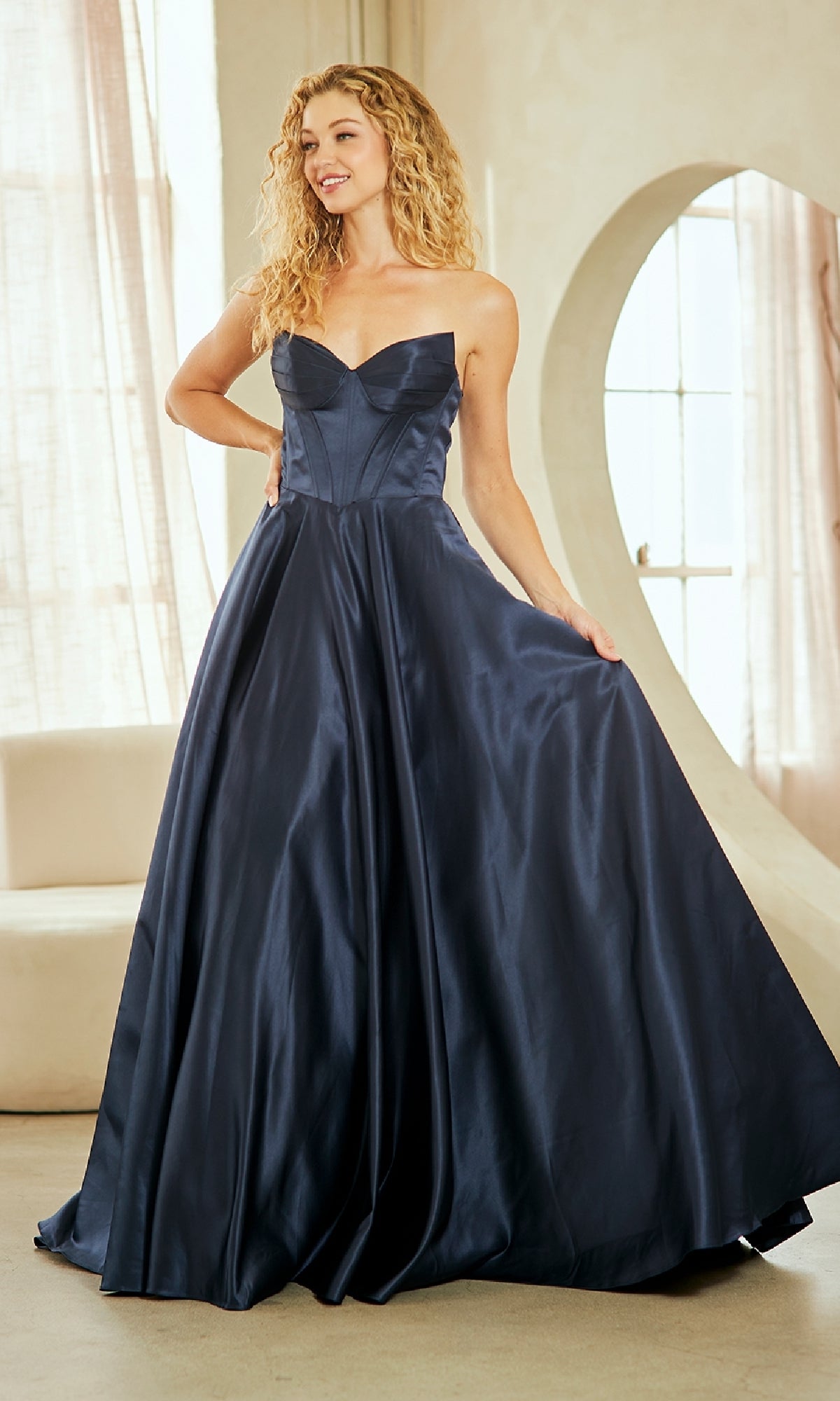 Woman wearing a navy blue evening gown with an a-line skirt in a well-lit room.